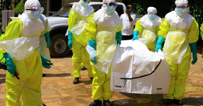 Équipes de santé en combinaison de protection près de tentes médicales et d’une ambulance sur une route boueuse à Biakato, en Ituri
