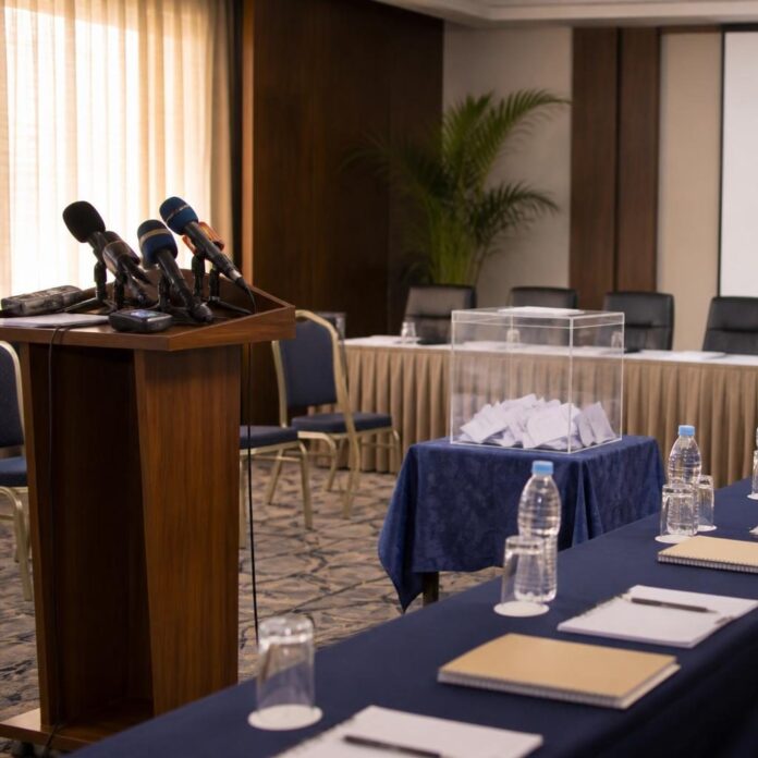 Salle de conférence à Kinshasa avec micros, documents et urnes symbolisant la lutte contre la corruption