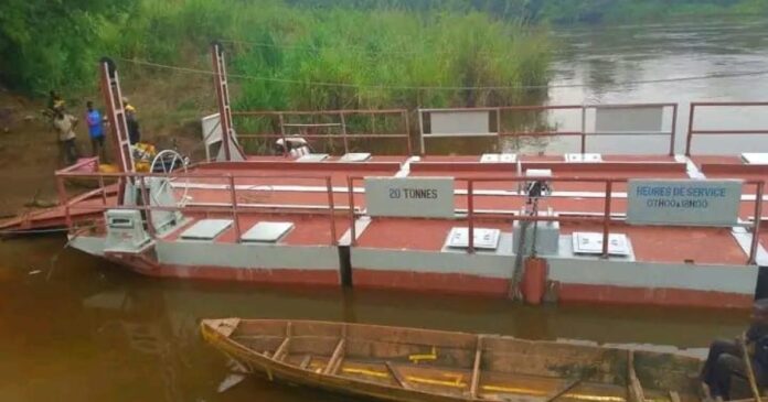 Bac remis en service amarré sur la rivière Kwango à Popokabaka, avec pirogues et sacs de marchandises sur la berge