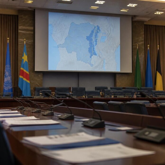 Salle de conférence onusienne à Genève avec documents et carte de l’Est de la RDC
