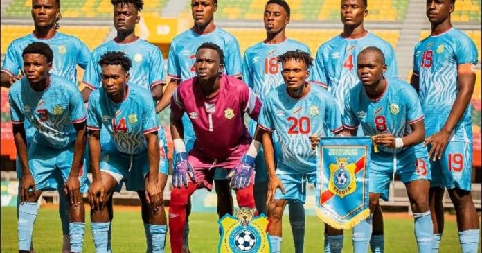 Jeunes footballeurs congolais en maillot bleu sur la pelouse d’un stade à Dakar, ballon au centre