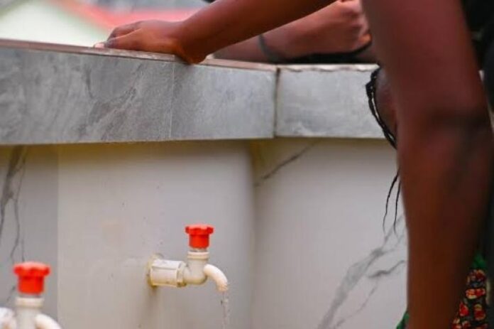 Des bidons et des installations de forage dans un quartier de Kinshasa, illustrant l’accès à l’eau et les risques de qualité