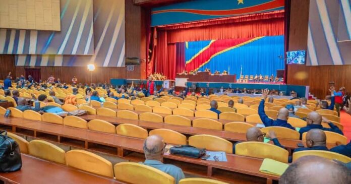 Hémicycle de l'Assemblée nationale avec pupitres, micros et dossiers parlementaires