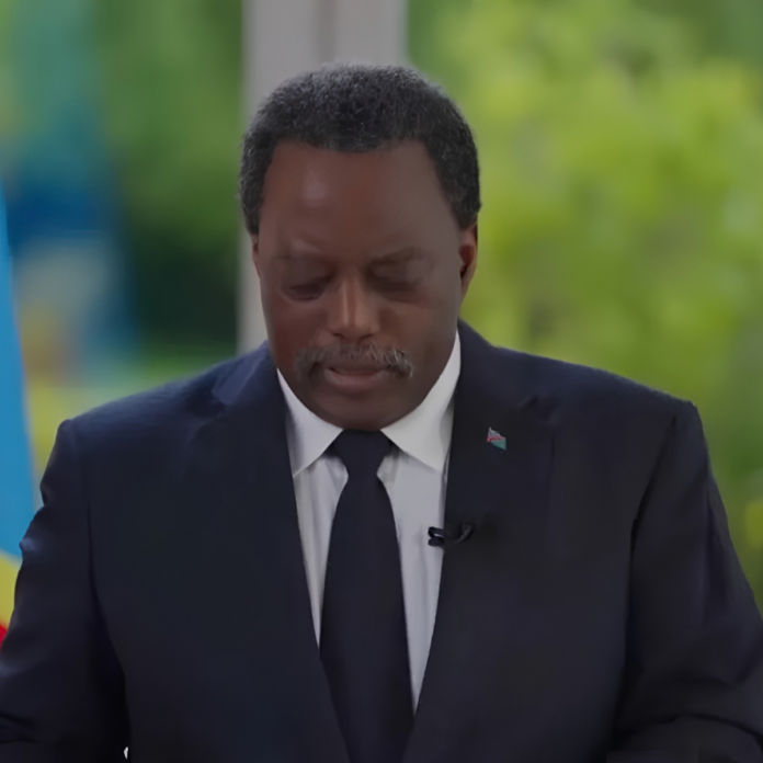 Pupitre de presse avec deux microphones devant un drapeau congolais, dans une salle de briefing à Kinshasa